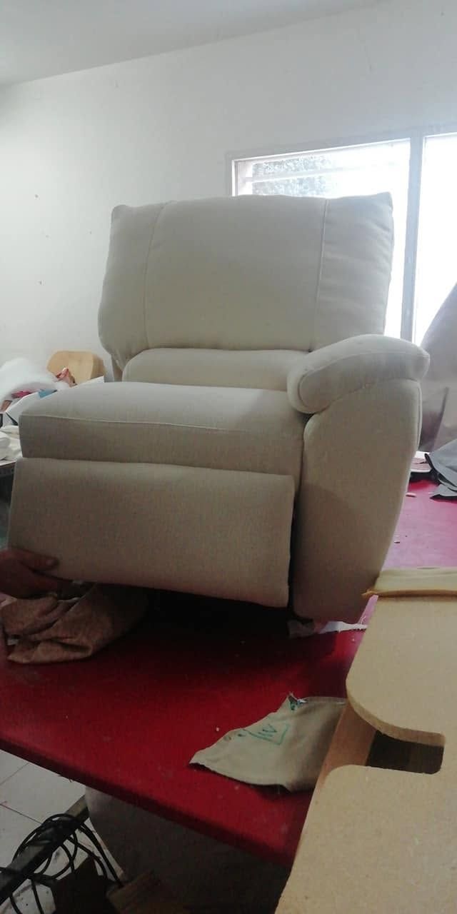 Un sillón blanco sobre una alfombra roja en una habitación soleada, con una ventana detrás.