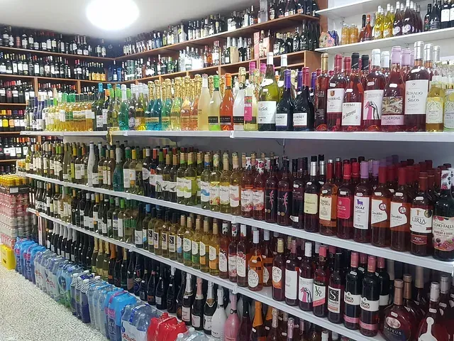 Estantes repletos de botellas de licor en una licorería bien surtida.