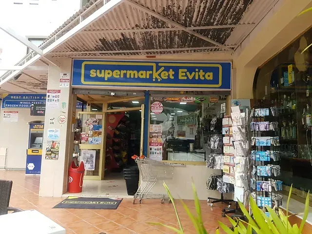 Fachada de supermercado Evita con cartel azul, puerta abierta y carrito de compra afuera.