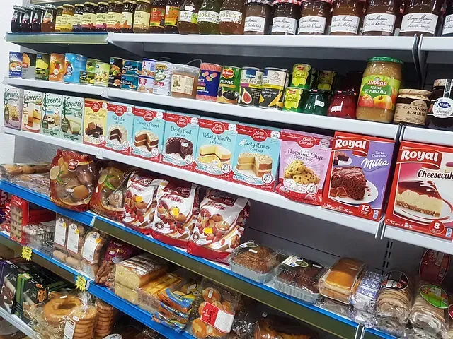Estantes de una tienda llenos de alimentos envasados, incluidas mezclas para pasteles, pan y frascos de conservas.