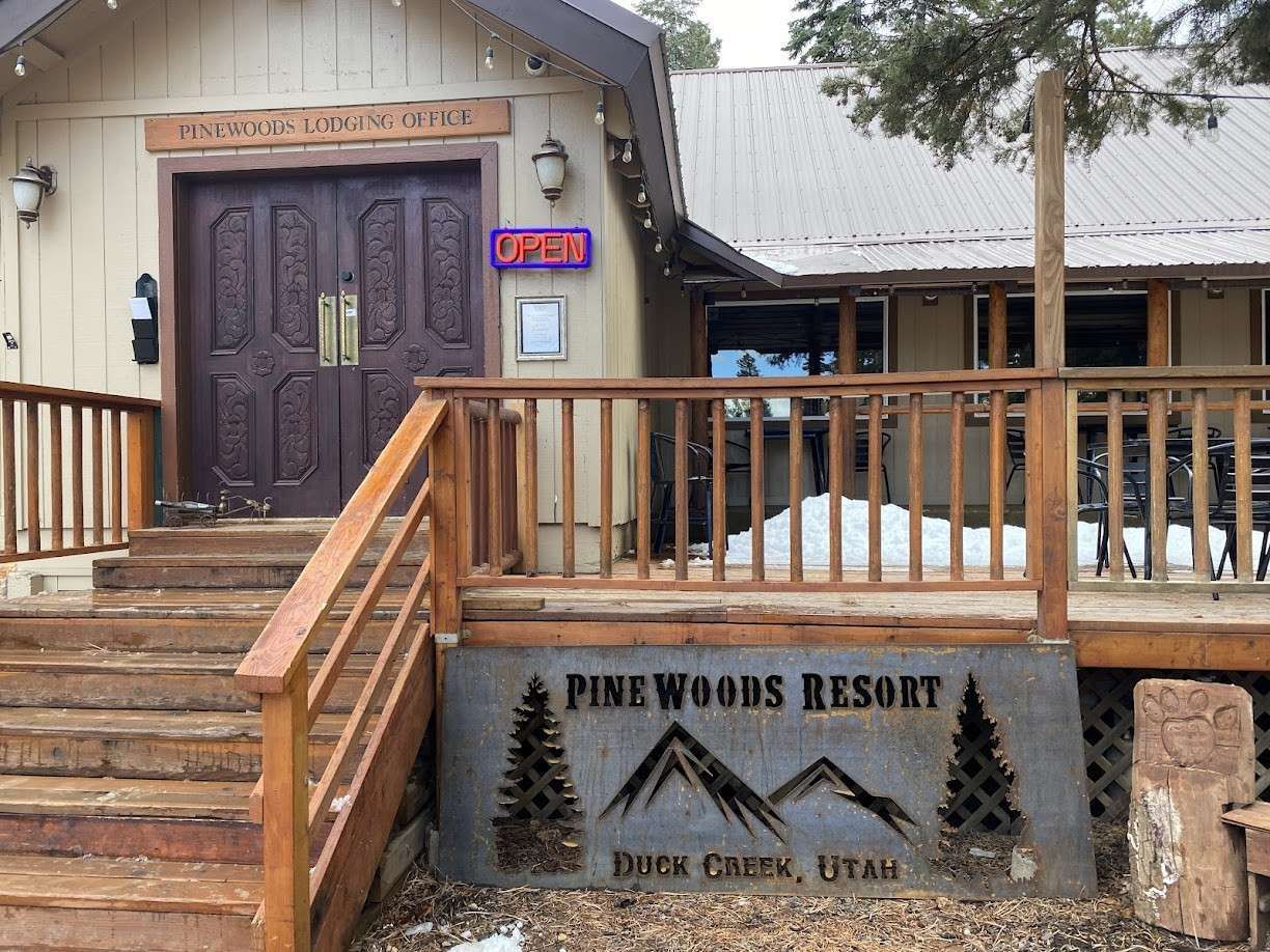 Exterior of Pinewoods Resort in Duck Creek, Utah, with steps leading to a wooden entrance.
