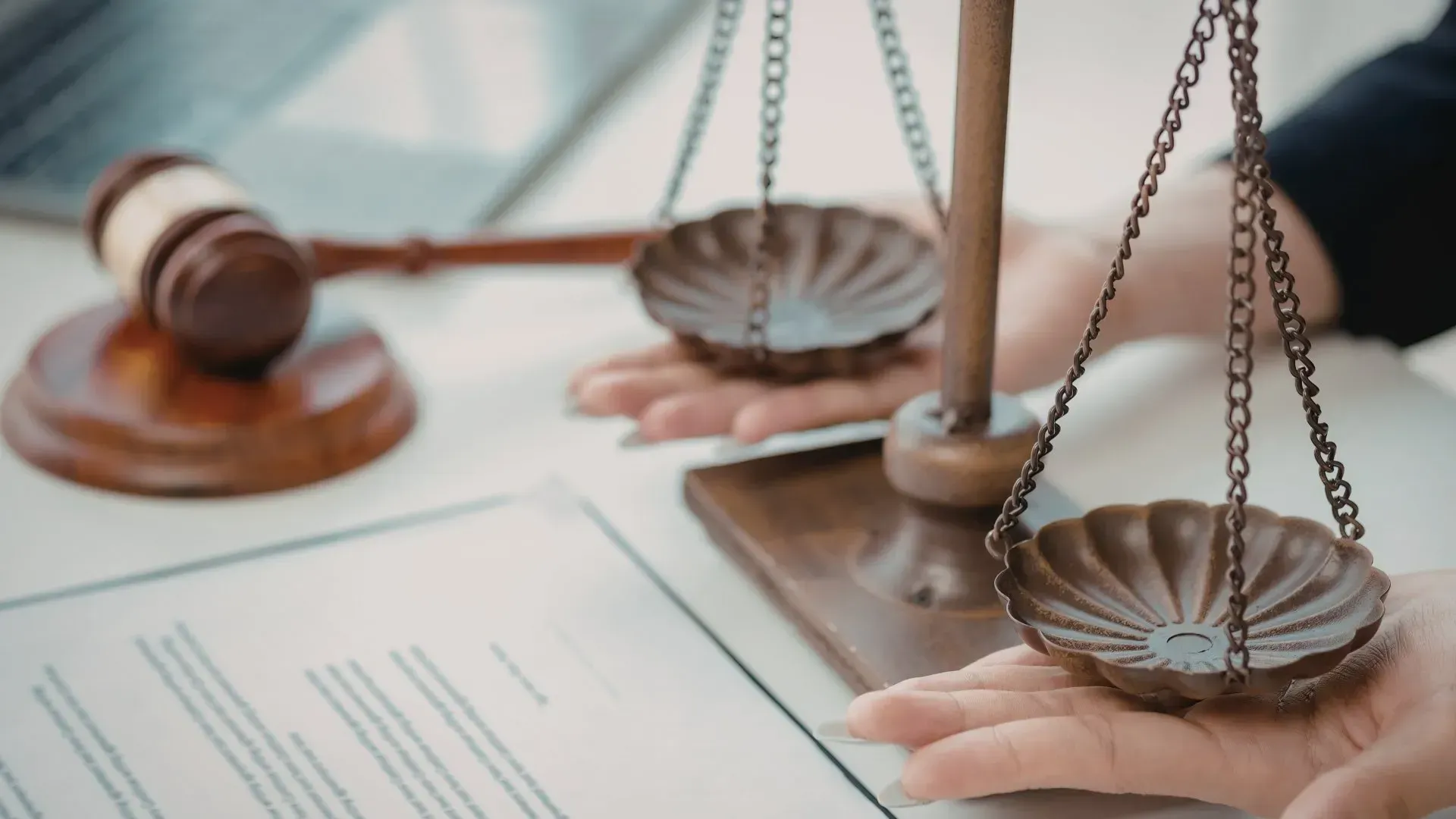 Balanza de la justicia, mazo y documentos sobre un escritorio, que simbolizan los procedimientos legales y la equidad.