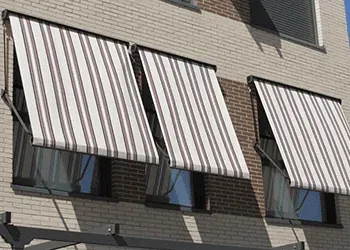 Un edificio de ladrillo con toldos de rayas en las ventanas.