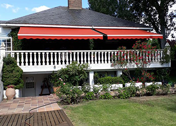 Una casa con un toldo rojo en el balcón.