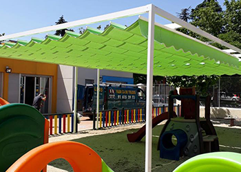 Un parque infantil con un toldo verde encima.