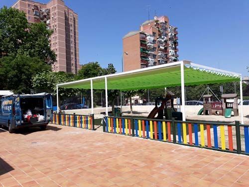 Una camioneta azul está estacionada frente a un parque infantil.