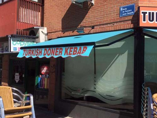 Un restaurante con un toldo azul que dice doner kebab turco