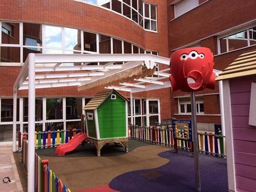 Un parque infantil con una casa verde y un pulpo rojo.