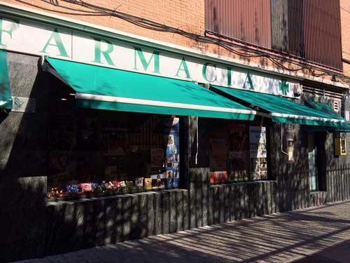 Un escaparate con un toldo verde que dice farmacia