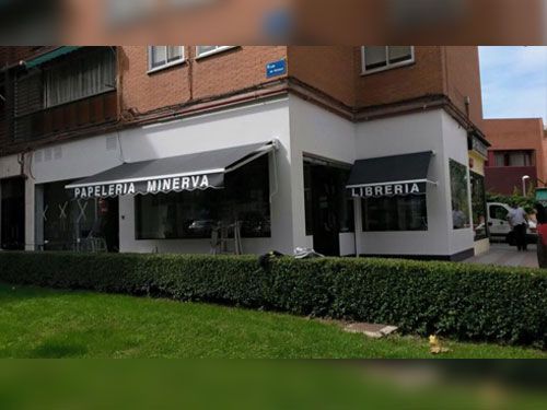 Un edificio blanco con un toldo negro que dice papeleria minerva