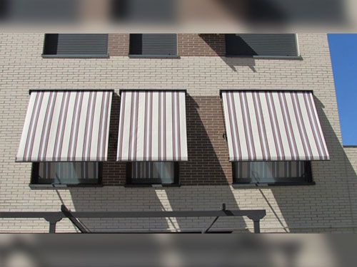 Un edificio de ladrillo con toldos de rayas en las ventanas.