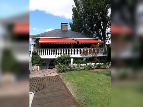 Una casa grande con un toldo rojo en el balcón.