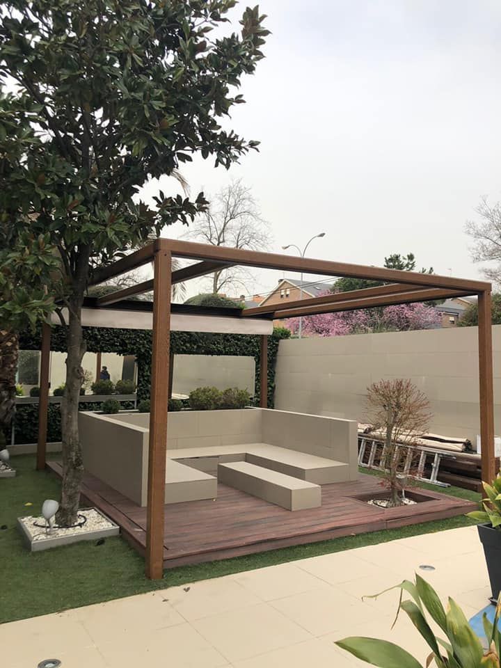 Una pérgola de madera con un sofá debajo en un patio trasero.