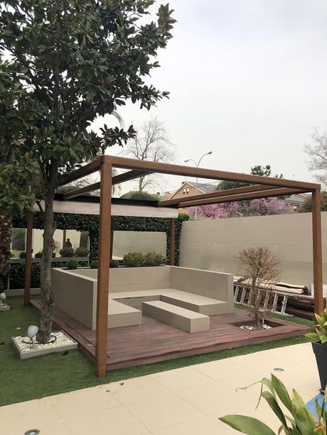 Una pérgola de madera con un sofá debajo en un patio trasero.