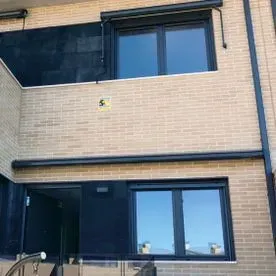 Un edificio de ladrillo con muchas ventanas y un coche aparcado delante.