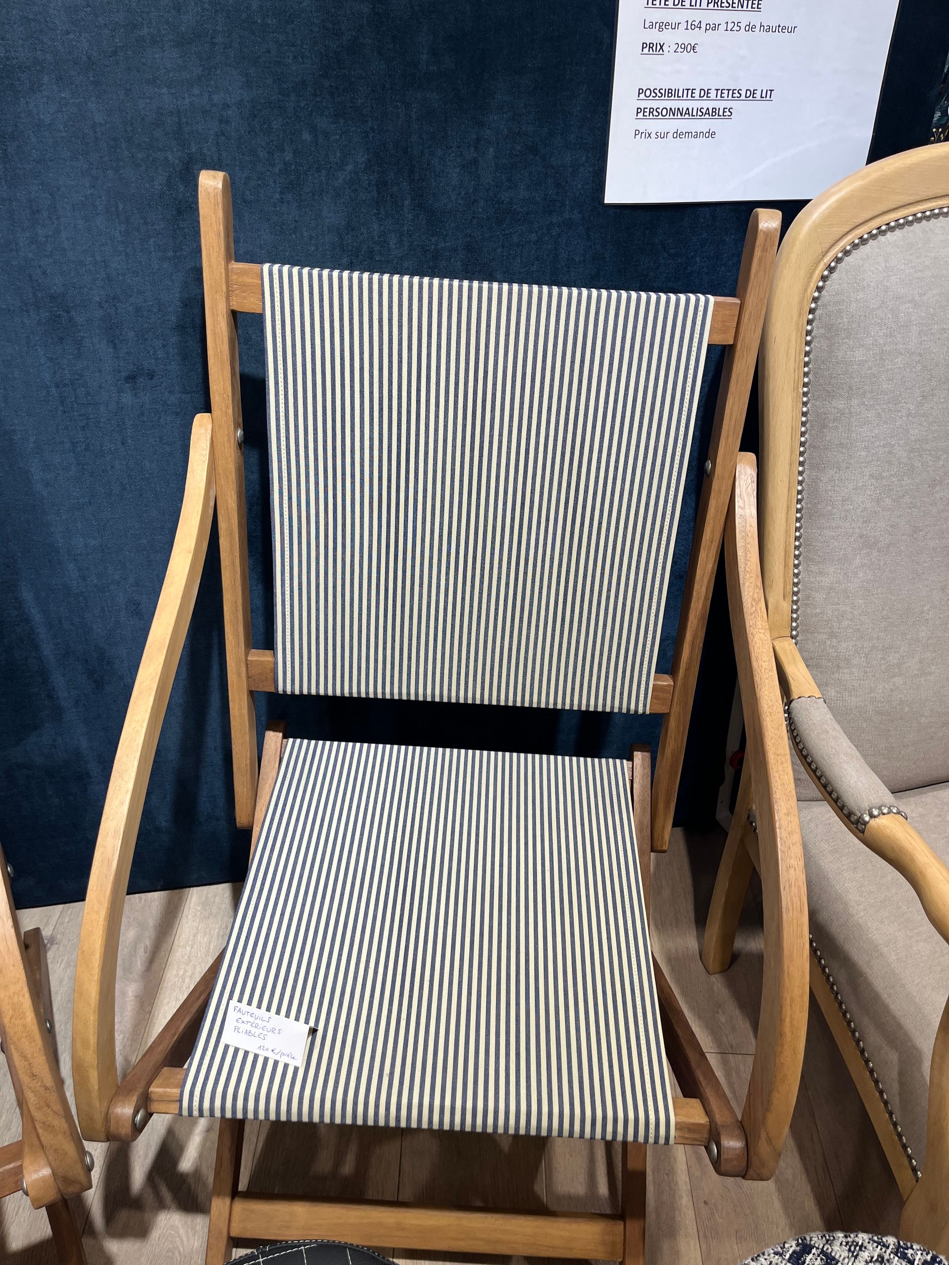 Une chaise pliante en bois avec assise et dossier en tissu à fines rayures noires et blanches.