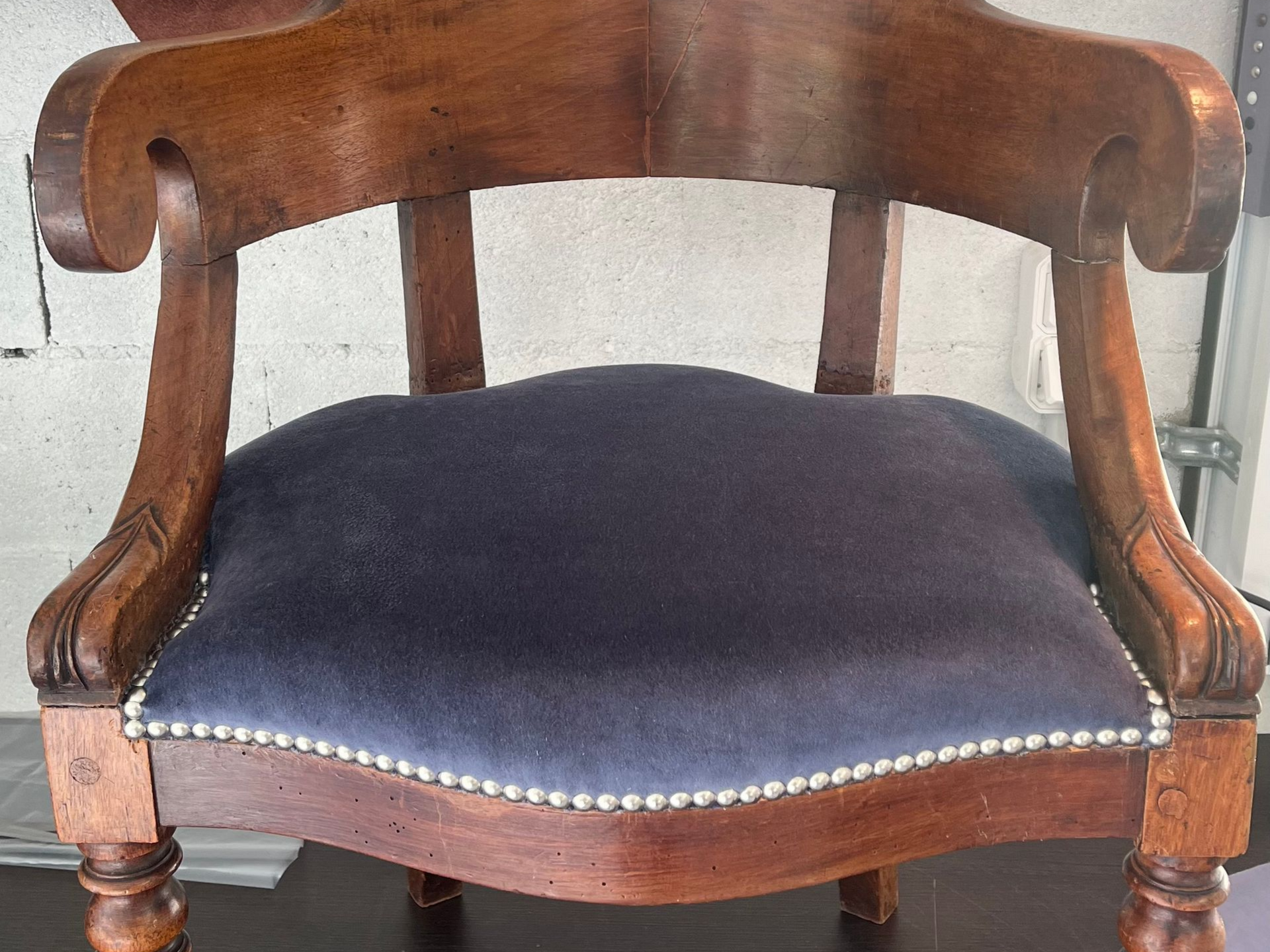 Un fauteuil en bois avec un dossier incurvé, des accoudoirs sculptés en volutes et une assise rembourrée.