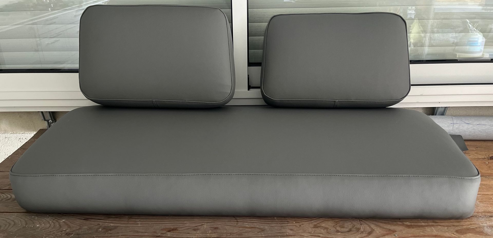 Deux coussins de dossier rectangulaires gris posés sur un coussin de banc gris plus grand.