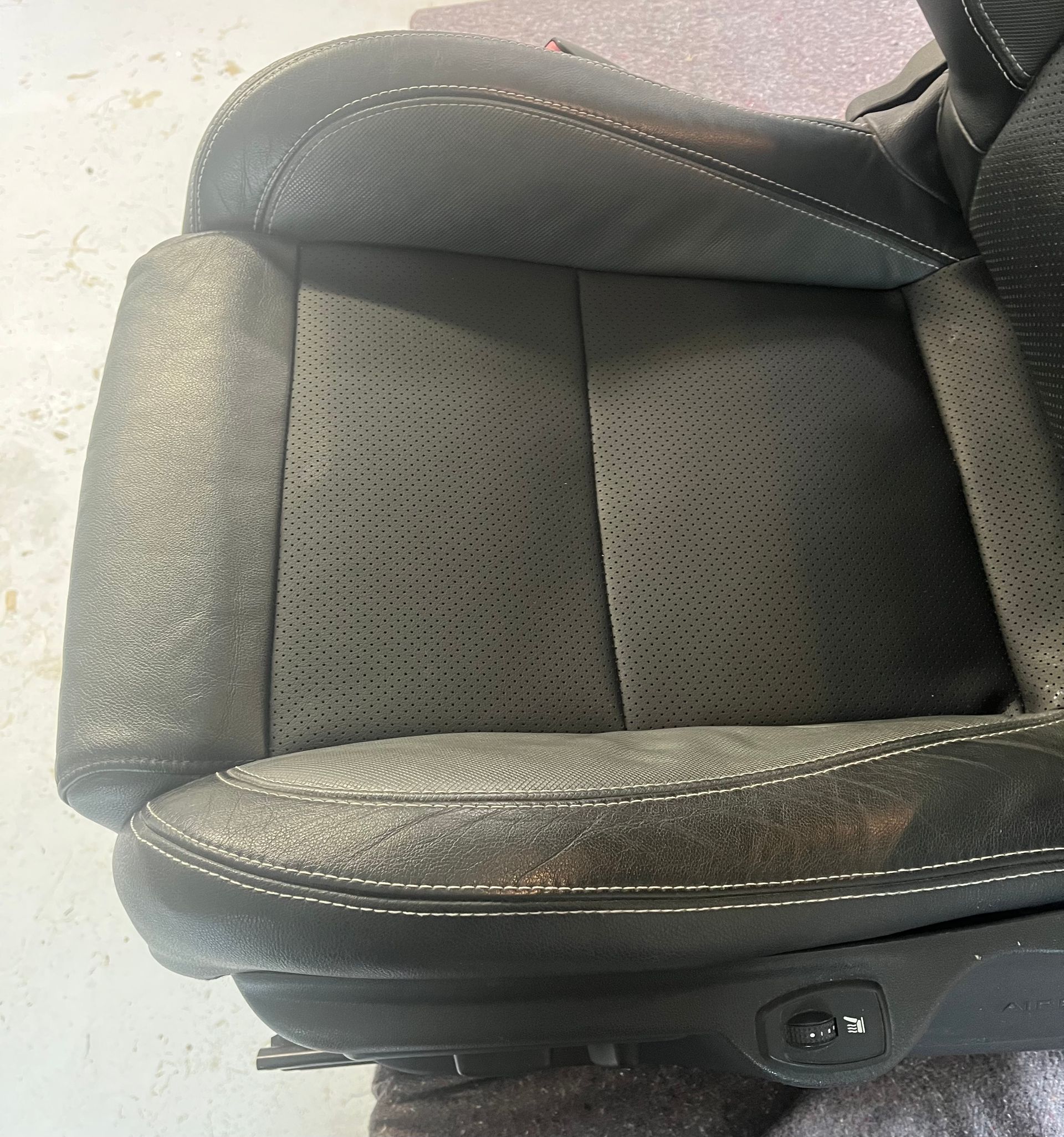 Un siège auto noir usé présentant d'importants dommages à la surface.