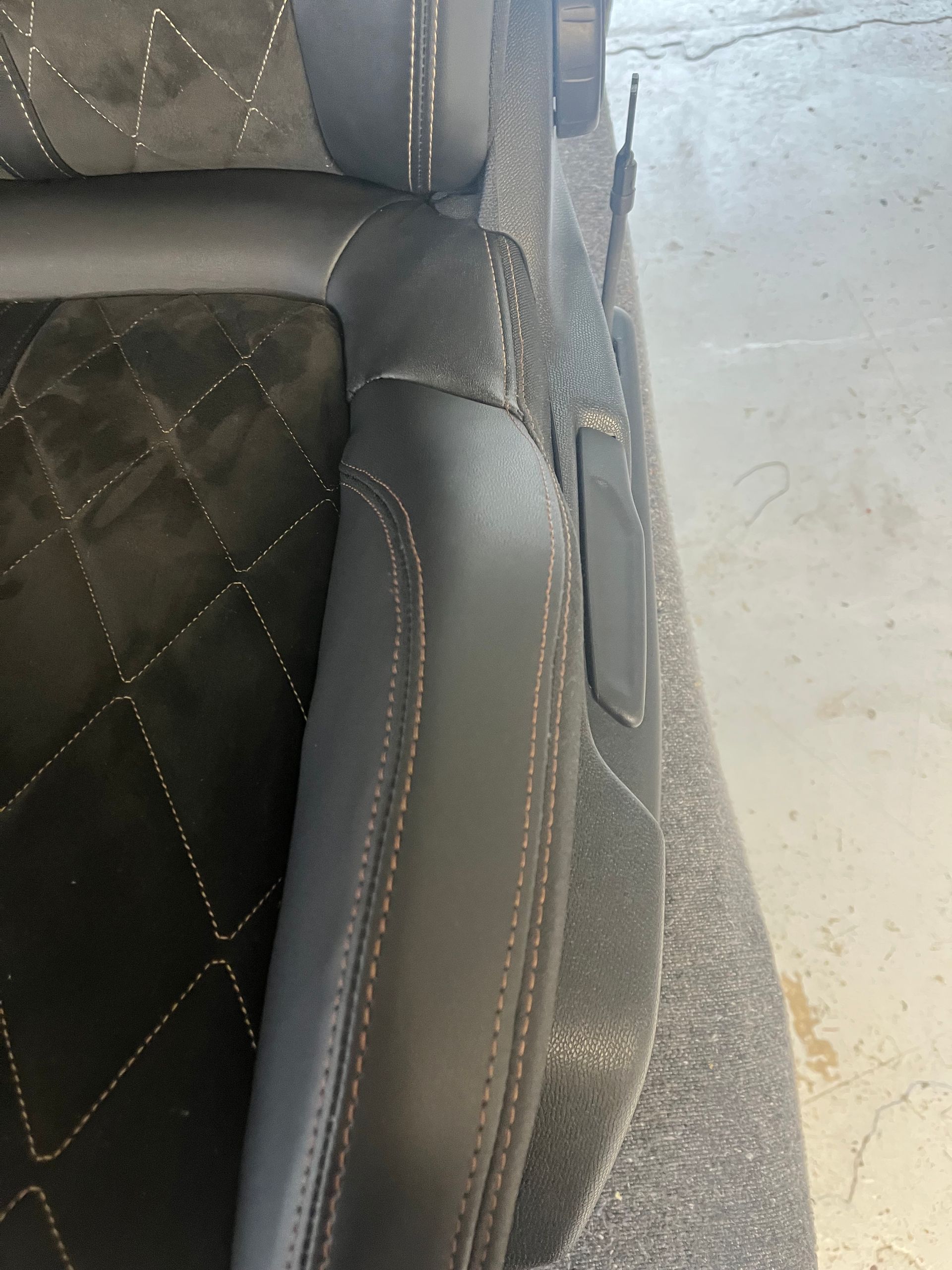 Gros plan sur un siège auto noir avec un rembourrage central matelassé en imitation daim.