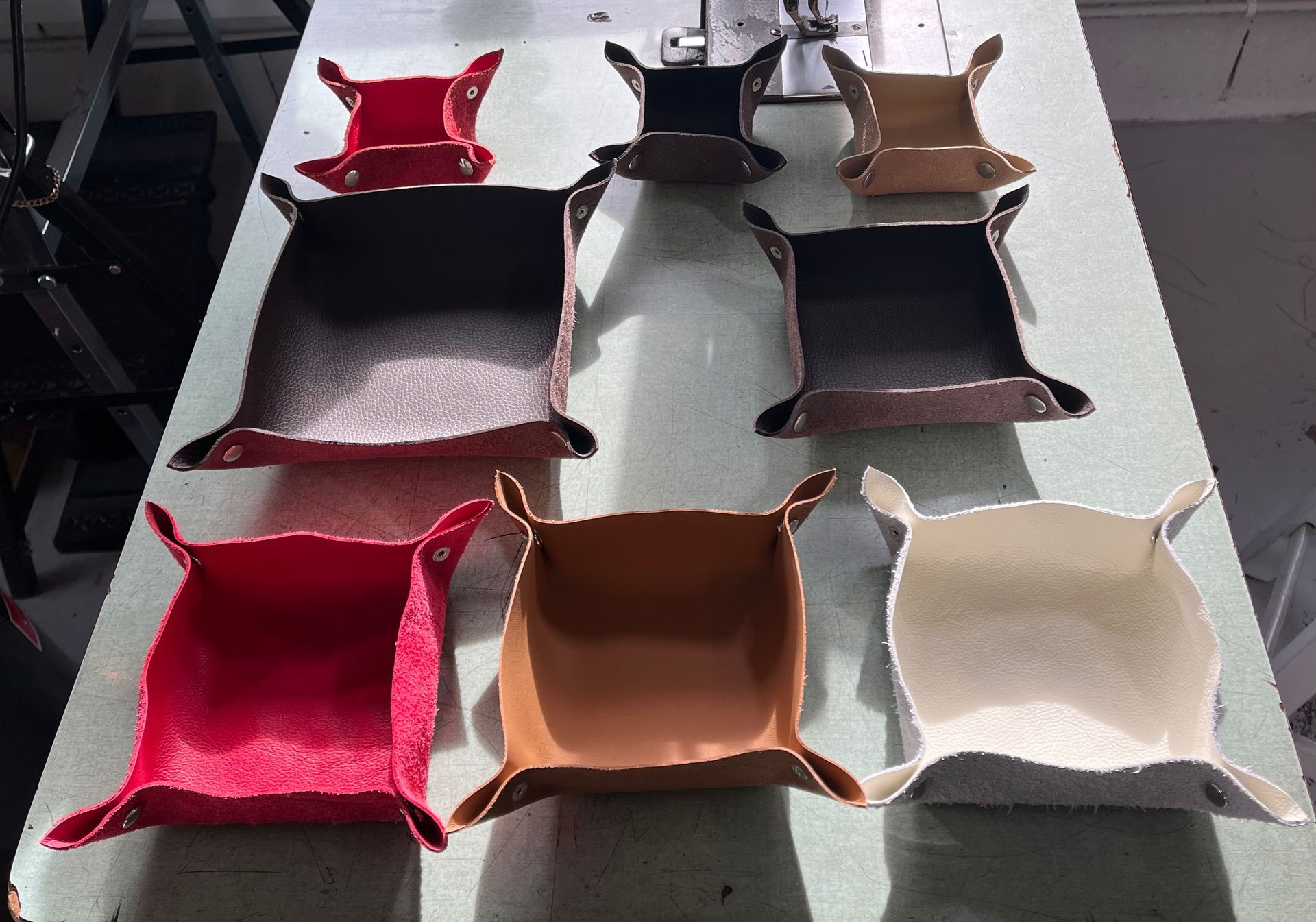 Divers plateaux fourre-tout en cuir faits à la main, de couleurs et de tailles différentes.