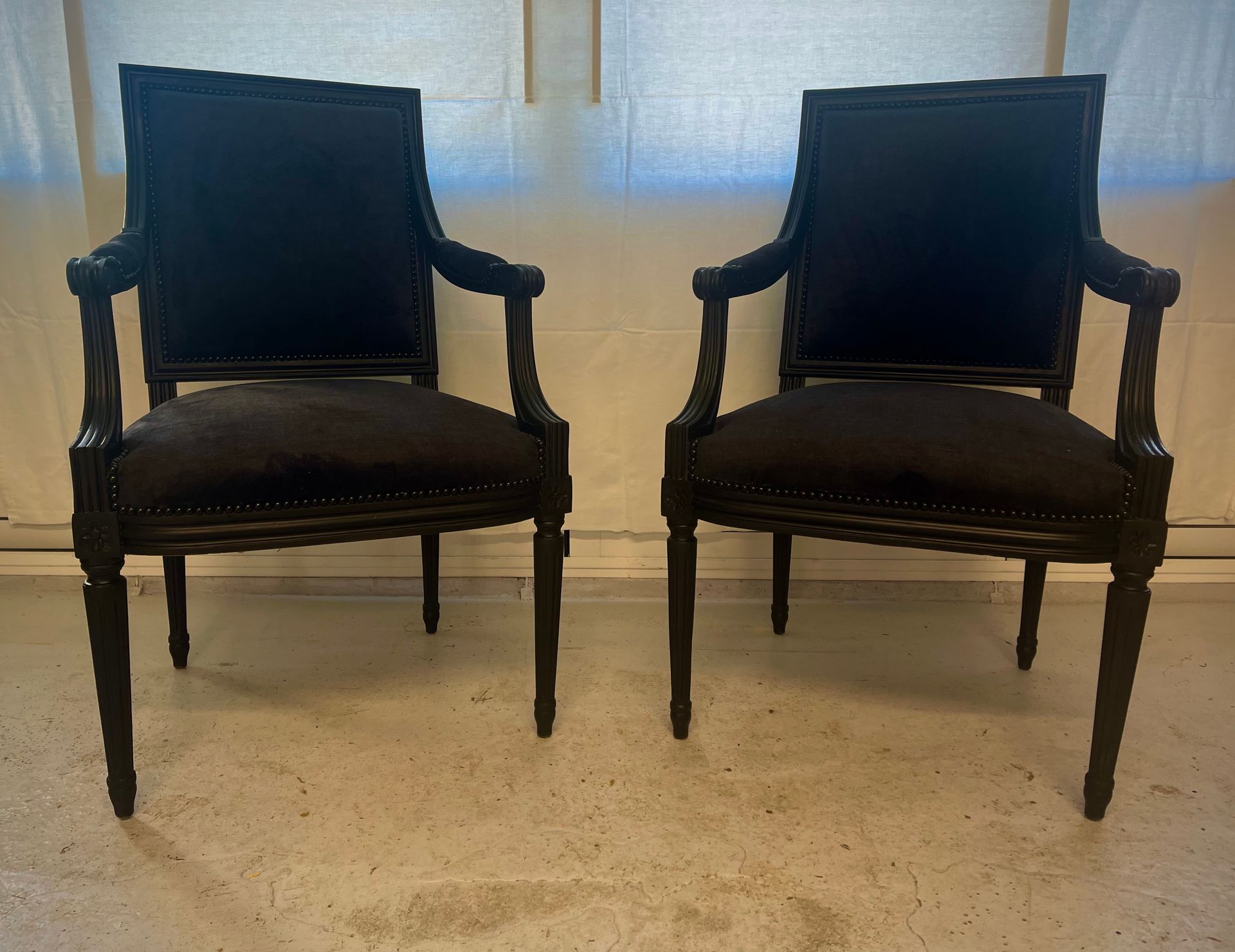 Deux fauteuils assortis, noirs, de style vintage, avec des cadres en bois foncé, sont placés côte à côte.