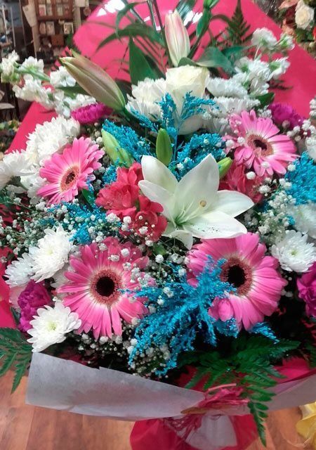 Un ramo de flores rosas y blancas con acentos azules.