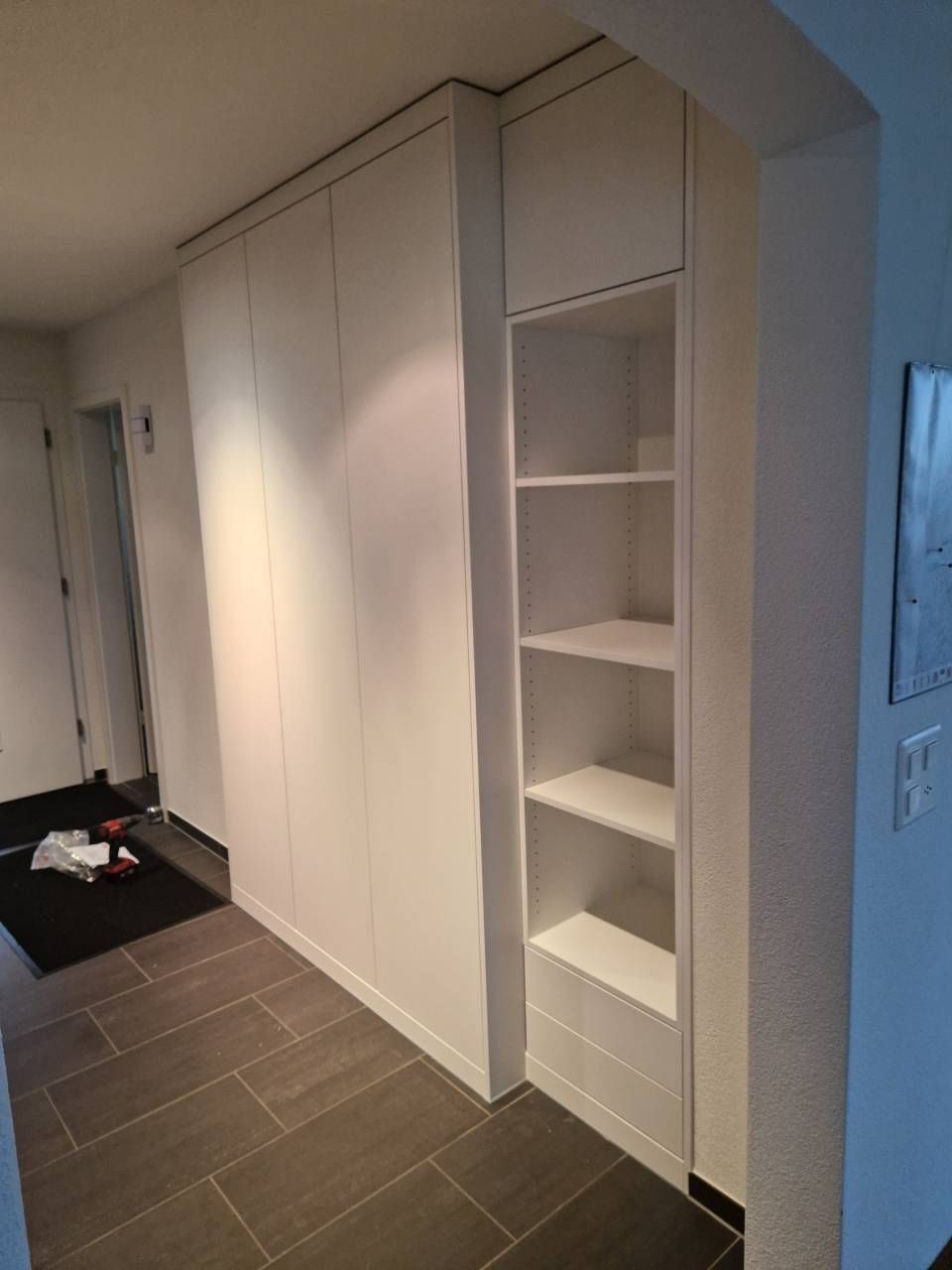 Weisser Büroflur mit verglasten Räumen und Türen. Hell erleuchtet durch Deckenleuchten.