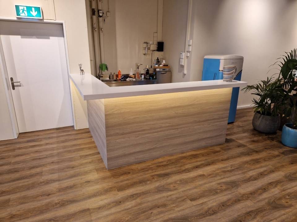 Leeres Zimmer mit türkisfarbenen Wänden, weissen Zierleisten, einem Fenster und grauem Fliesenboden.