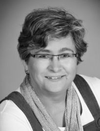 Ein Schwarzweißfoto einer Frau mit Brille und Kopftuch.
