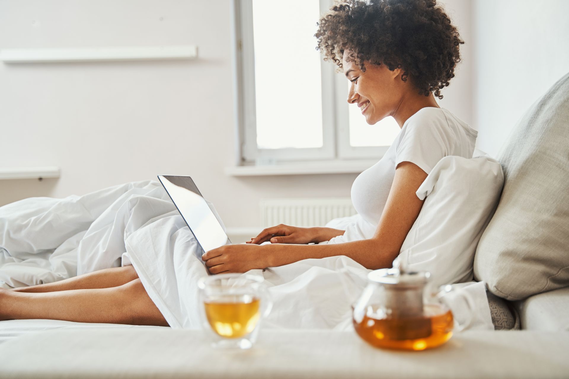 Une femme souriante sur un lit