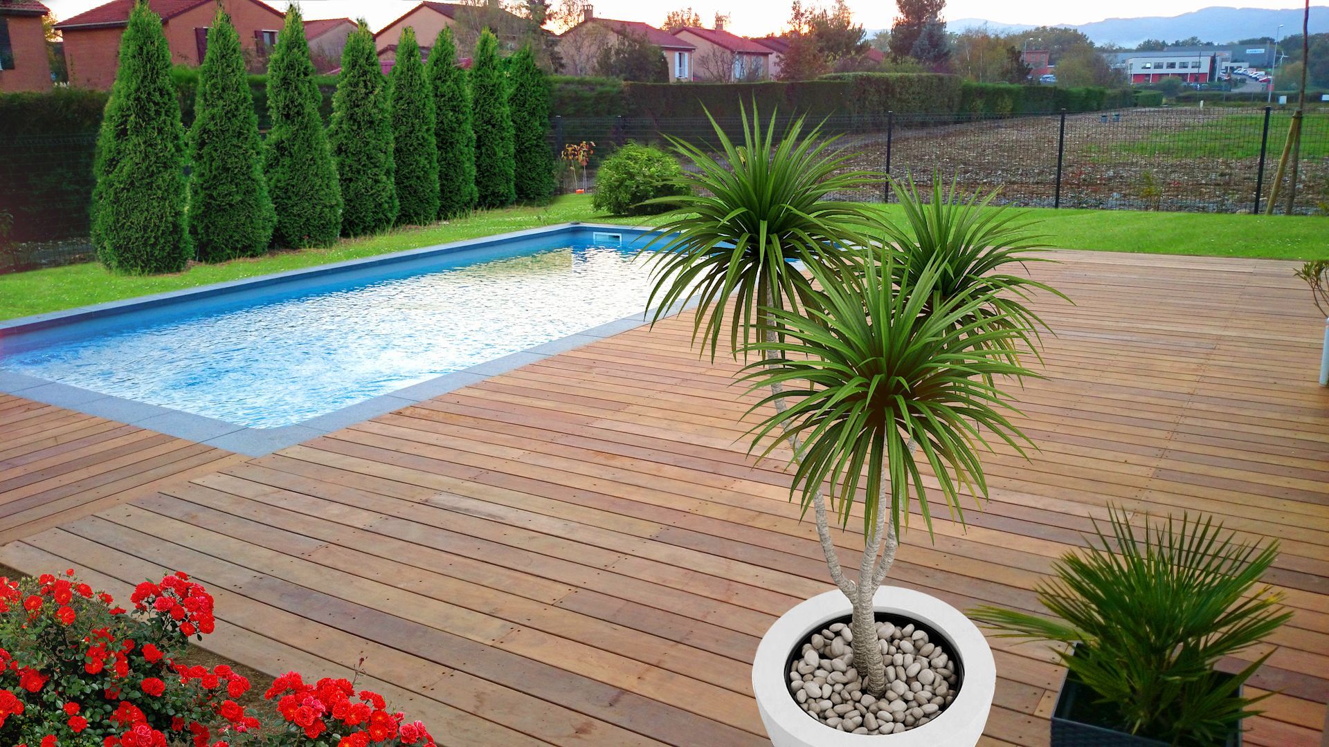 Une piscine entourée d'une terrasse en bois, de plantes en pot et d'arbres taillés avec soin.
