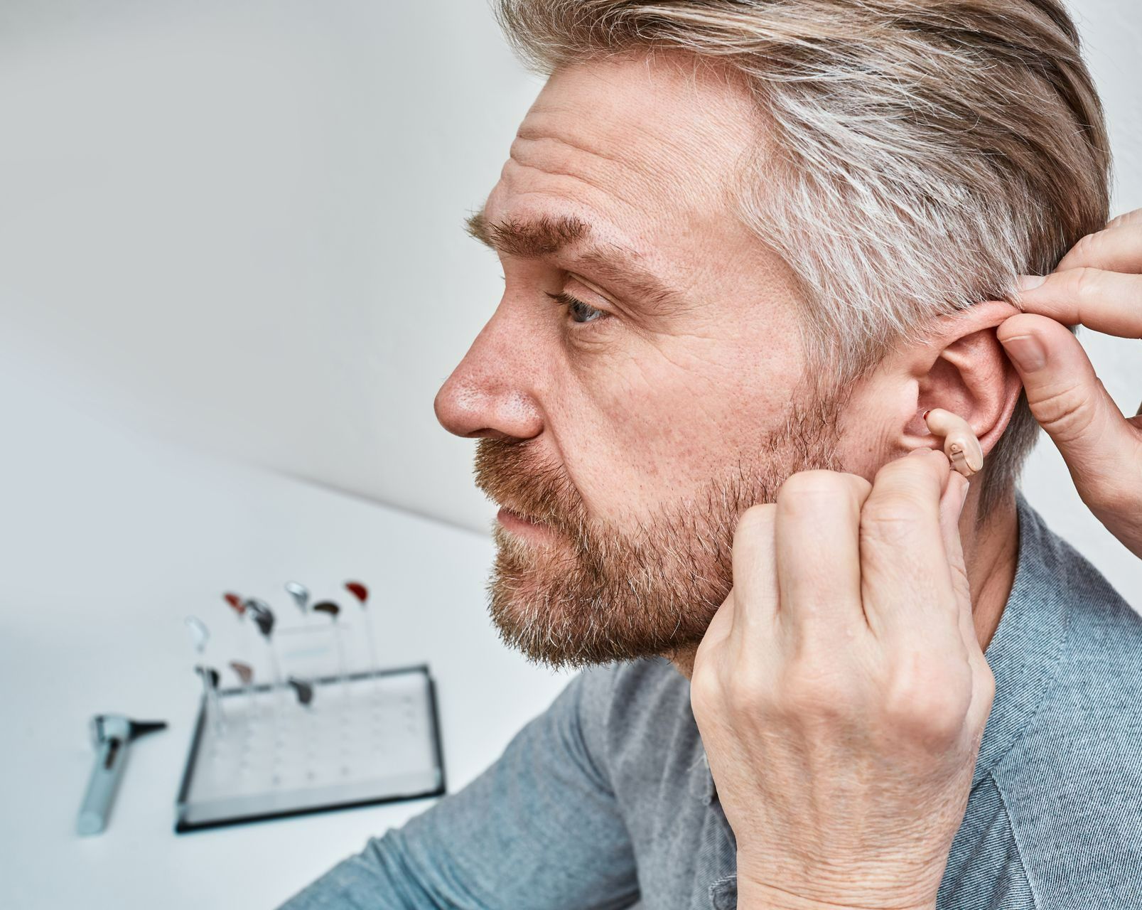 Un homme se fait mettre un appareil auditif de type intra-auriculaire