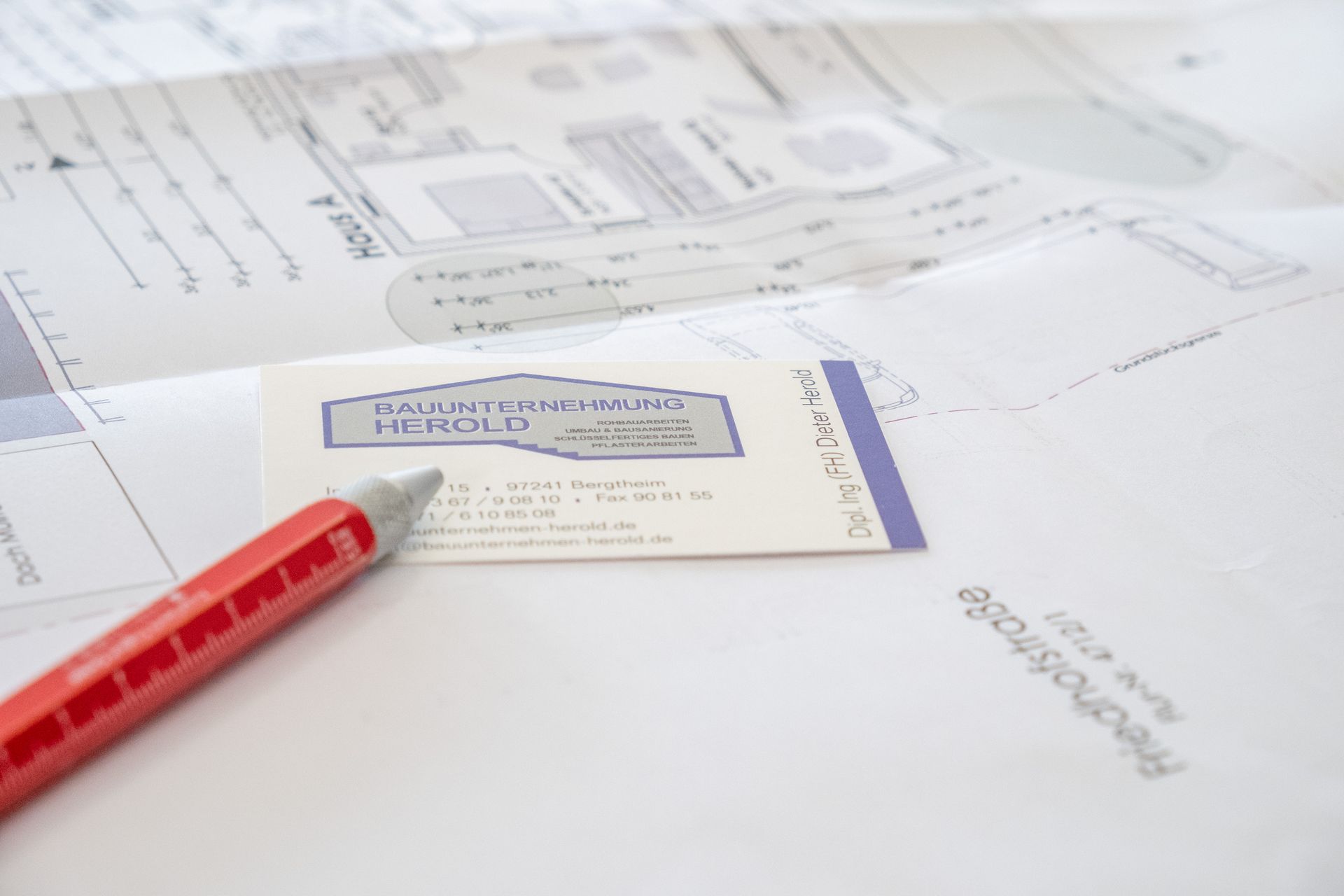 Hand mit Stift zeichnet auf Bauplan, Bauunternehmen Herold
