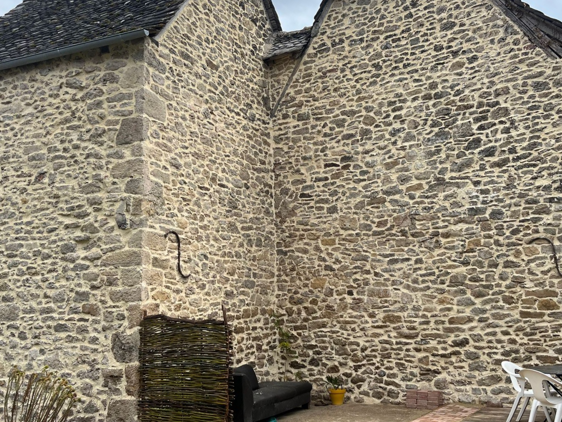 Extérieur d'un bâtiment en pierre avec coin, sièges et une pièce décorative en fer forgé.
