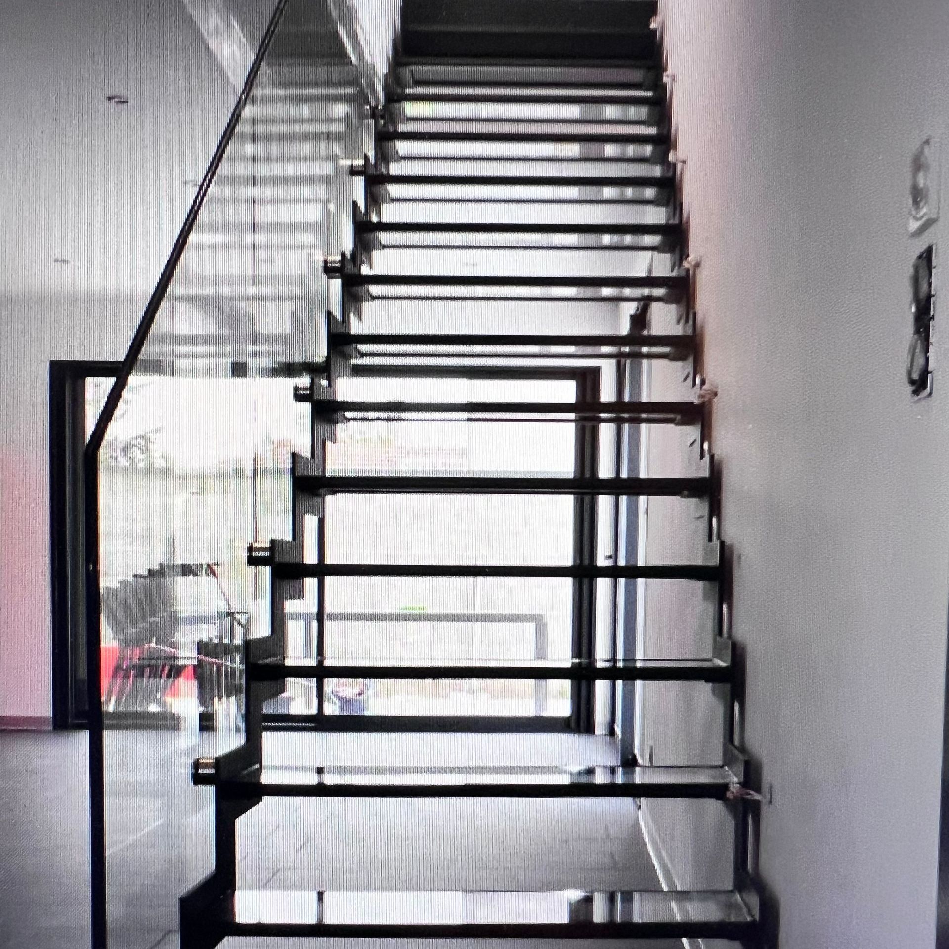 Escalier métallique vu de face avec garde-corps en verre