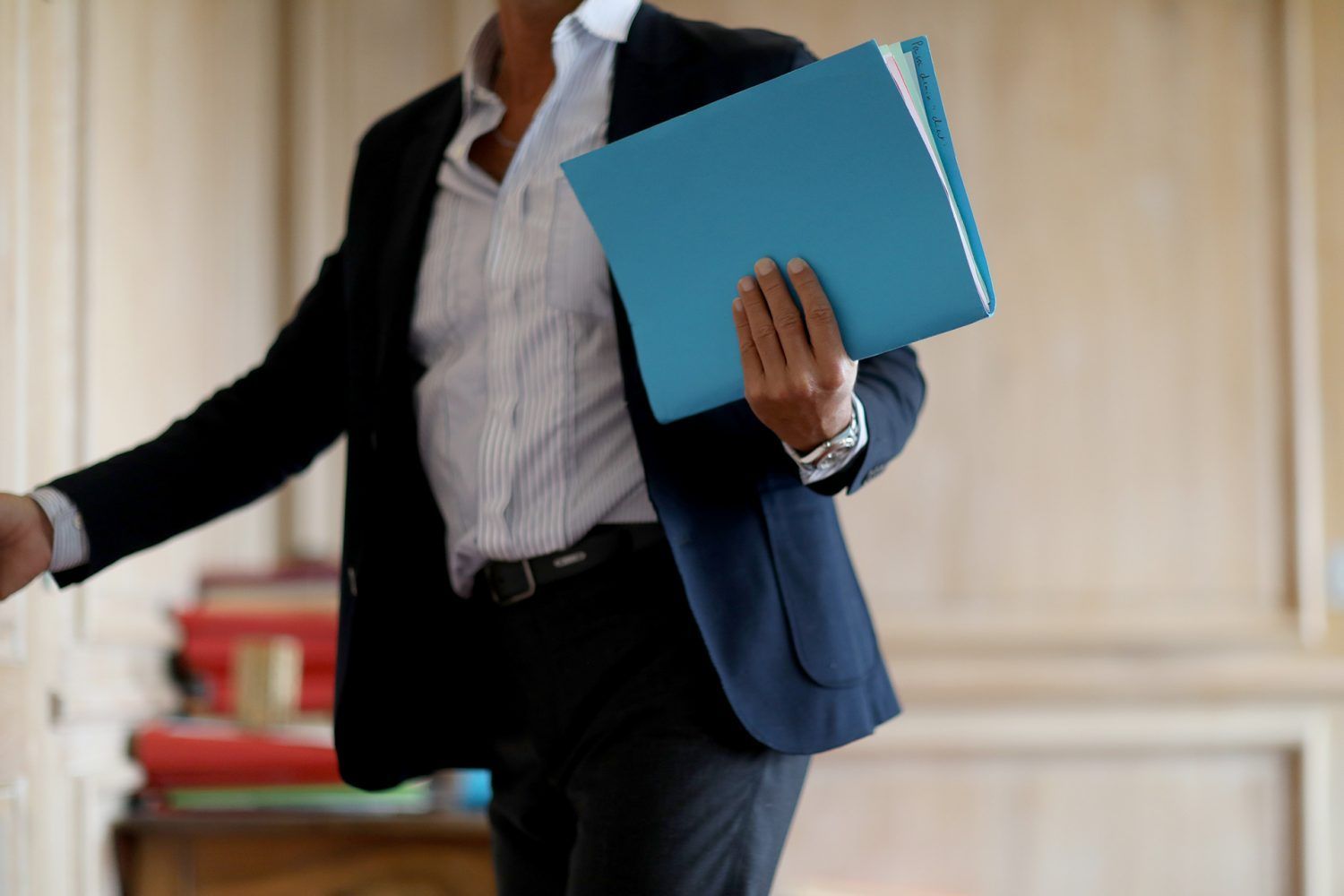 Un avocat tient un dossier à la couverture bleue