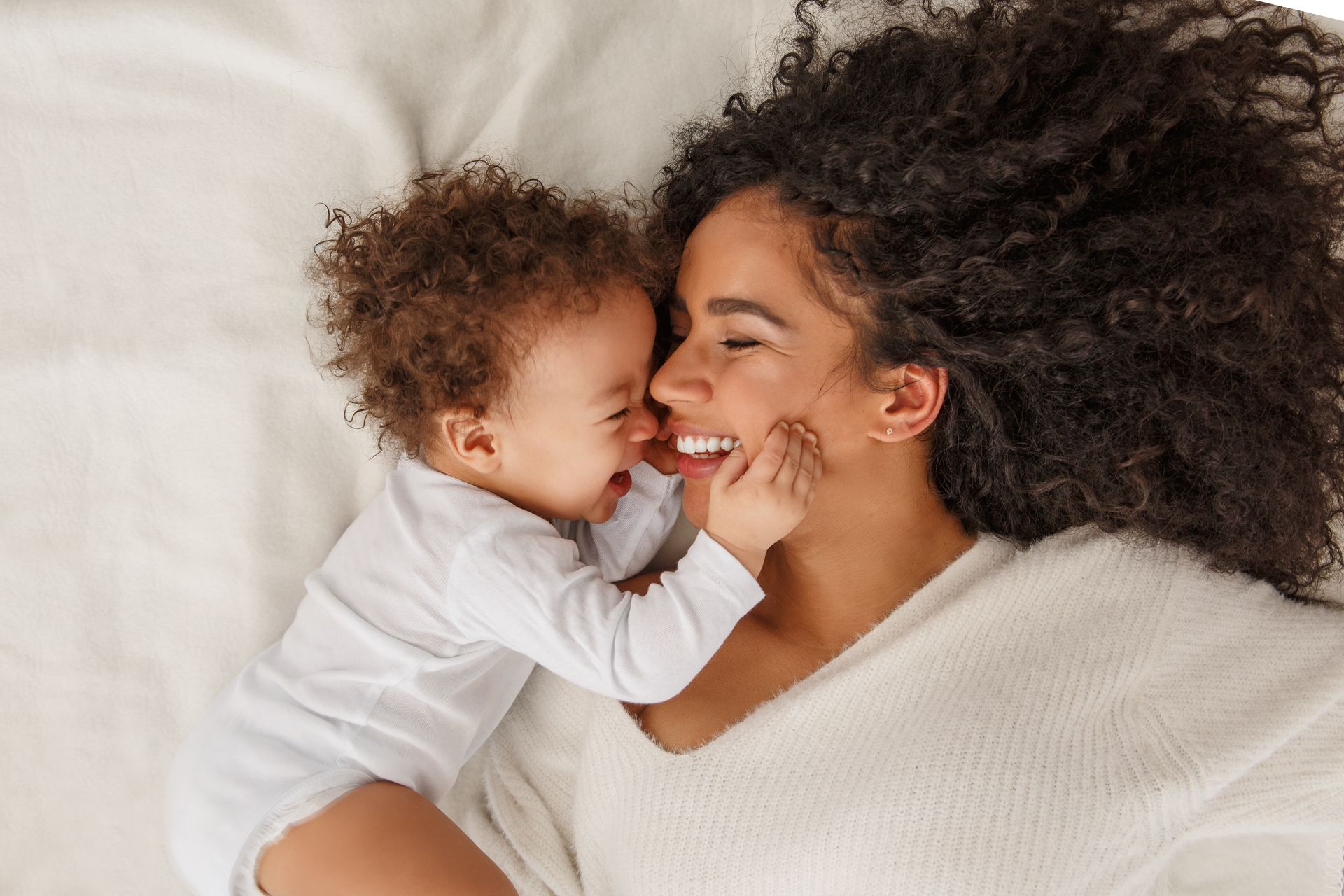 Une femme allongée avec son bébé contre son visage
