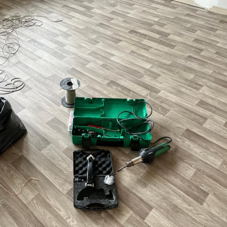 Outils pour travaux électriques sur un sol stratifié : fer à souder et boîte à outils.