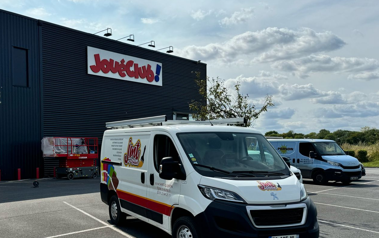 Une camionnette de JMT Peinture garée devant une boutique JouéClub .