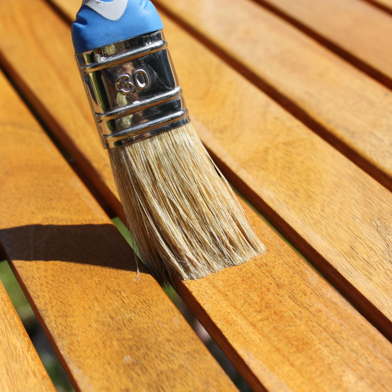 Un pinceau appliquant une finition sur une surface en bois.