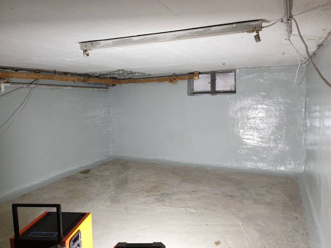 Kellerraum mit gestrichenen Wänden, einem kleinen Fenster und einem Hauswirtschaftskasten.