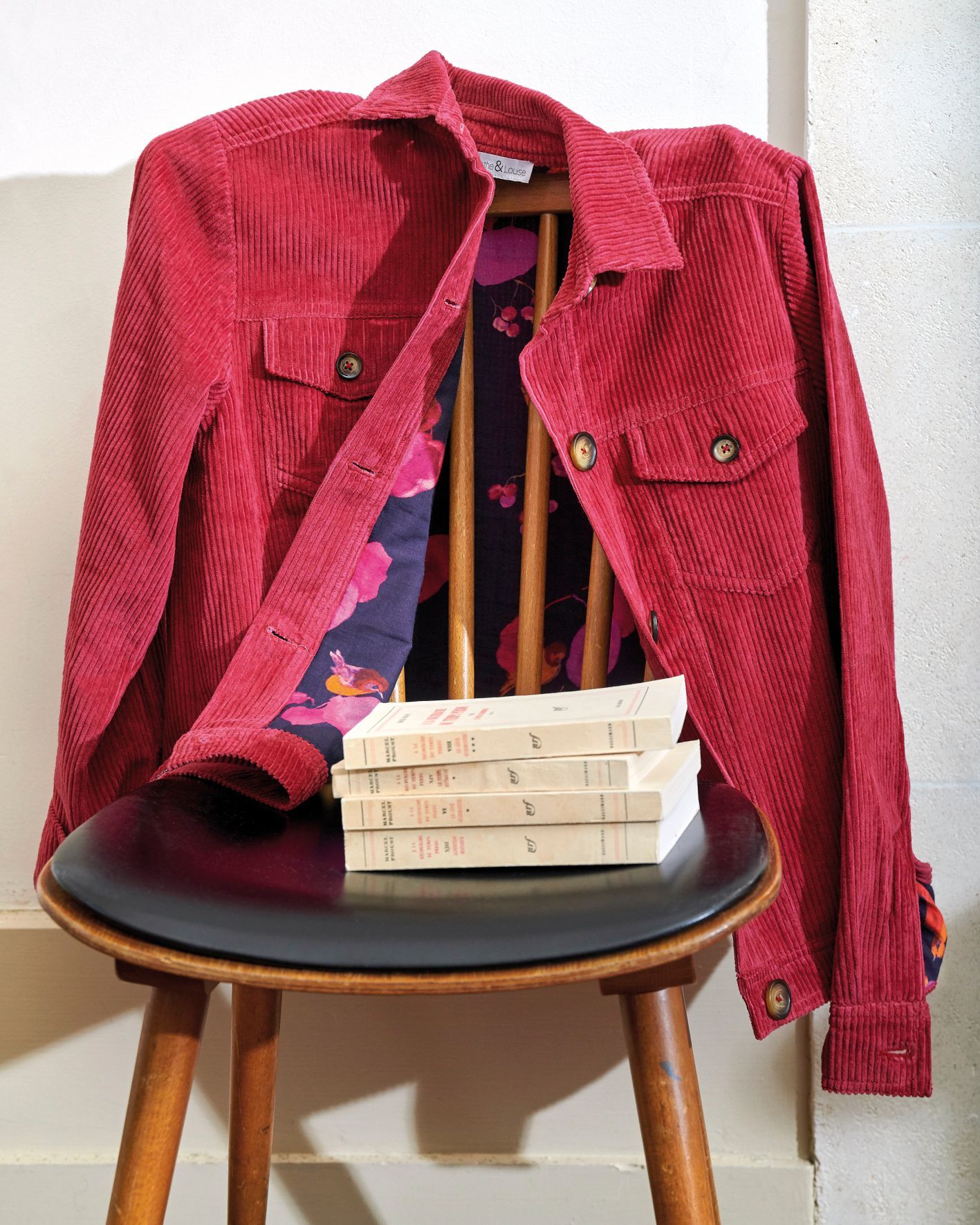 Veste posée sur un tabouret, avec une pile de livres sur l’assise.