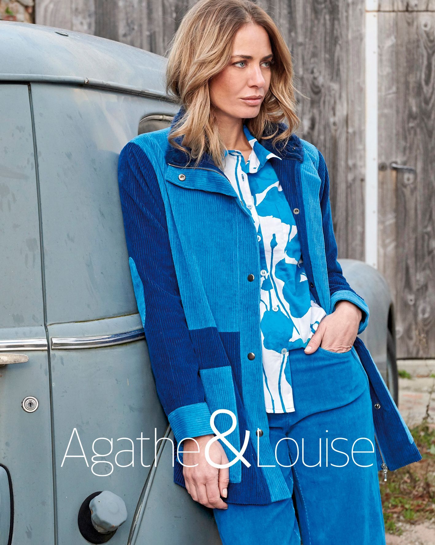 Femme en manteau et haut à motifs debout à côté d’un van vintage en extérieur.