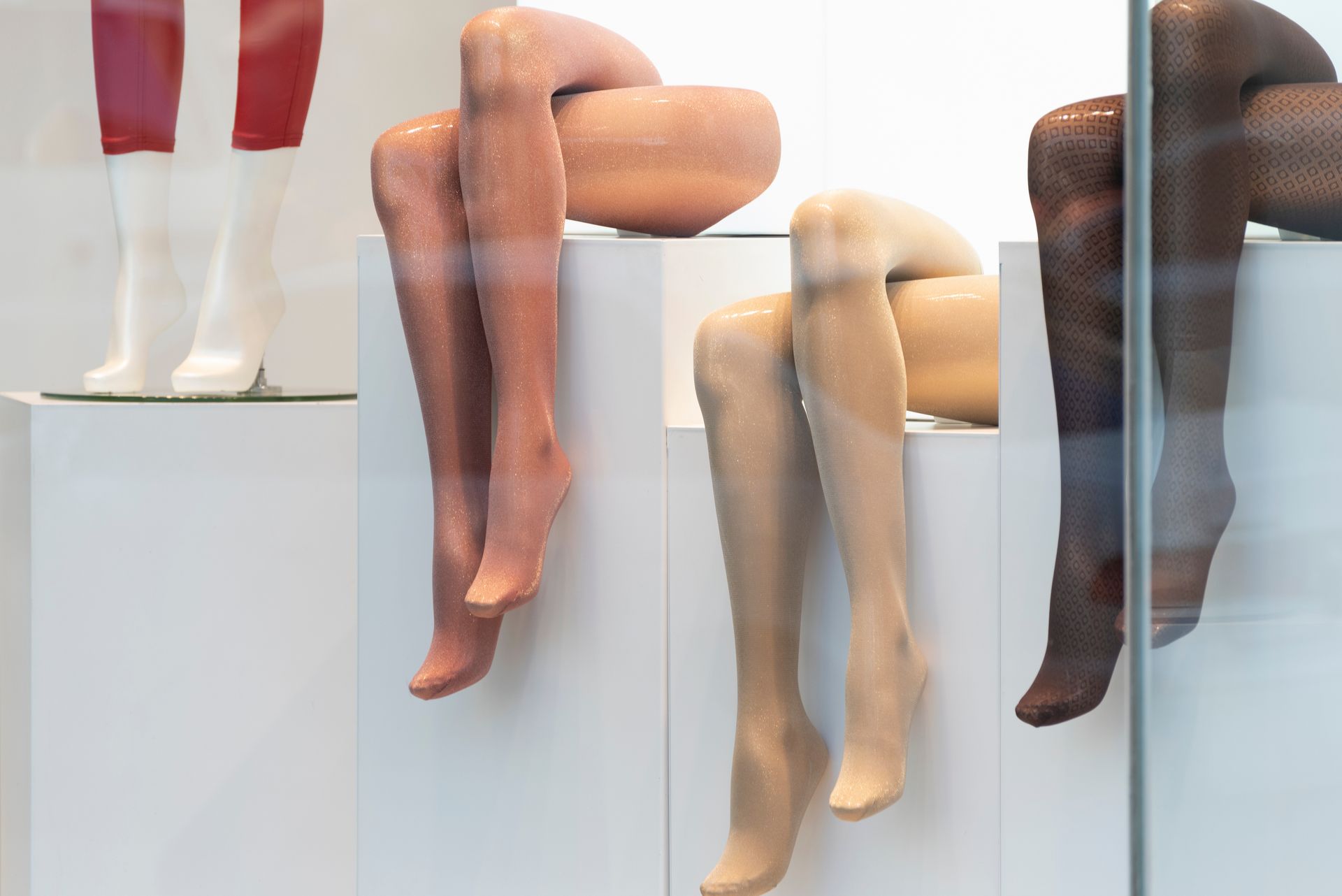 Rangée de jambes de mannequins portant des collants, exposées sur des socles.