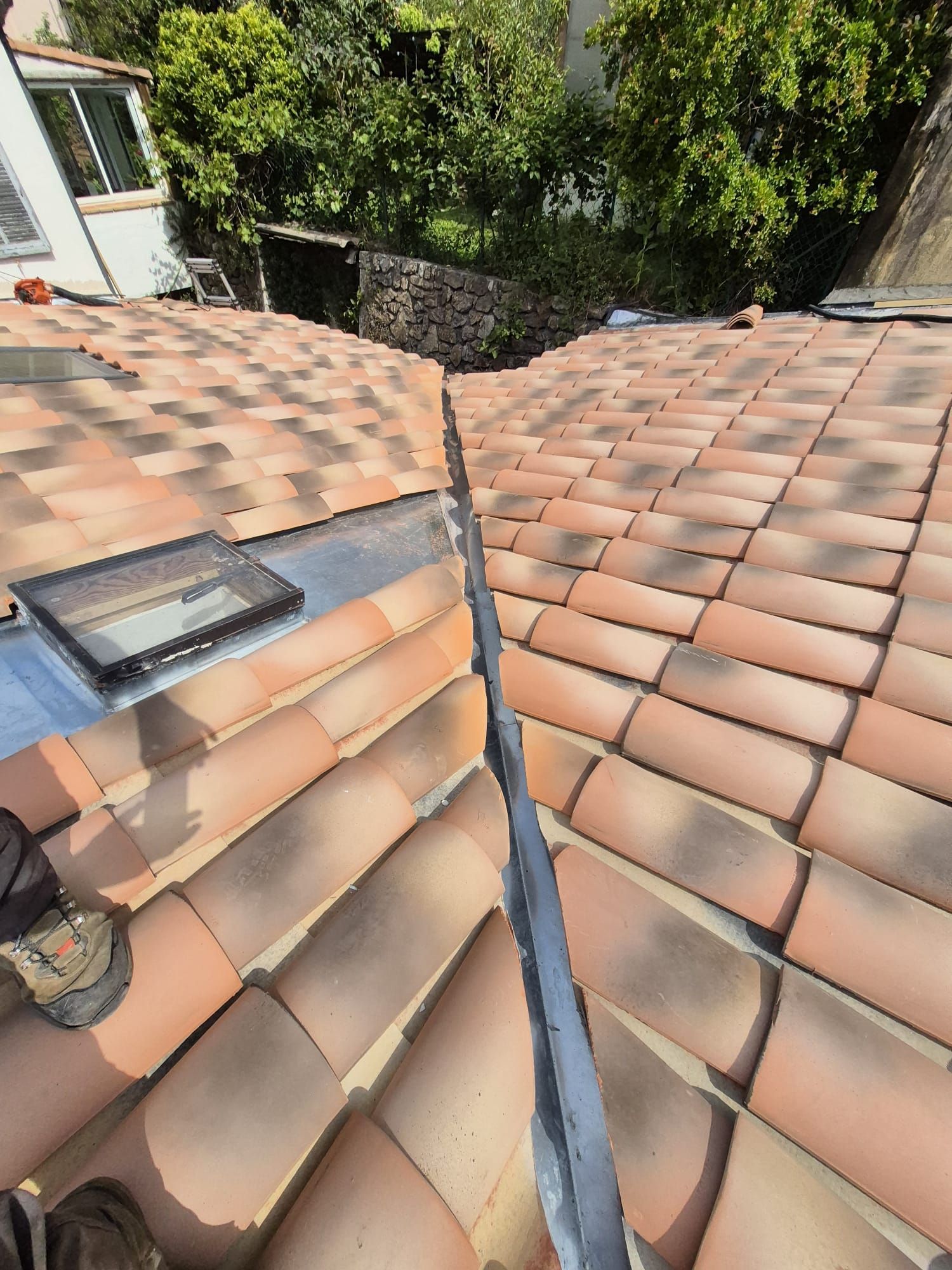 Toiture en tuiles de terre cuite avec noue métallique et puits de lumière ; extérieur.