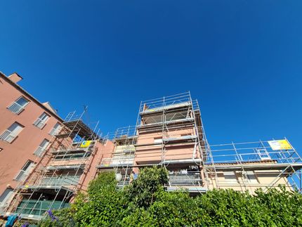 Un bâtiment en construction avec des échafaudages autour et un ciel bleu en arrière-plan.