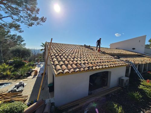 Un homme travaille sur le toit d'une maison