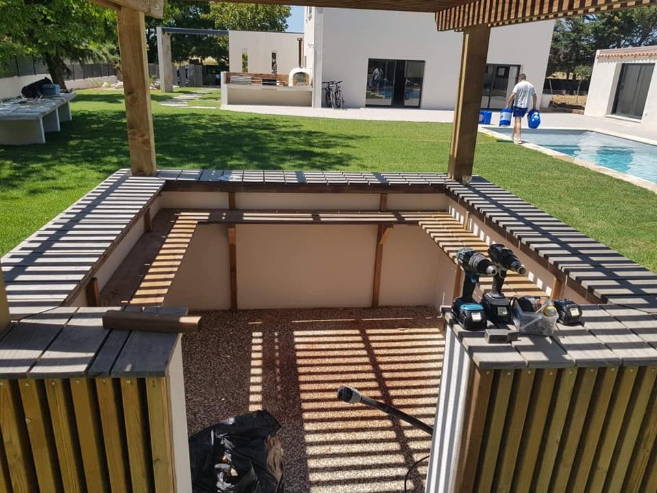 Terrasse extérieure avec barbecue intégré et pergola, à côté d'une piscine et de villas modernes