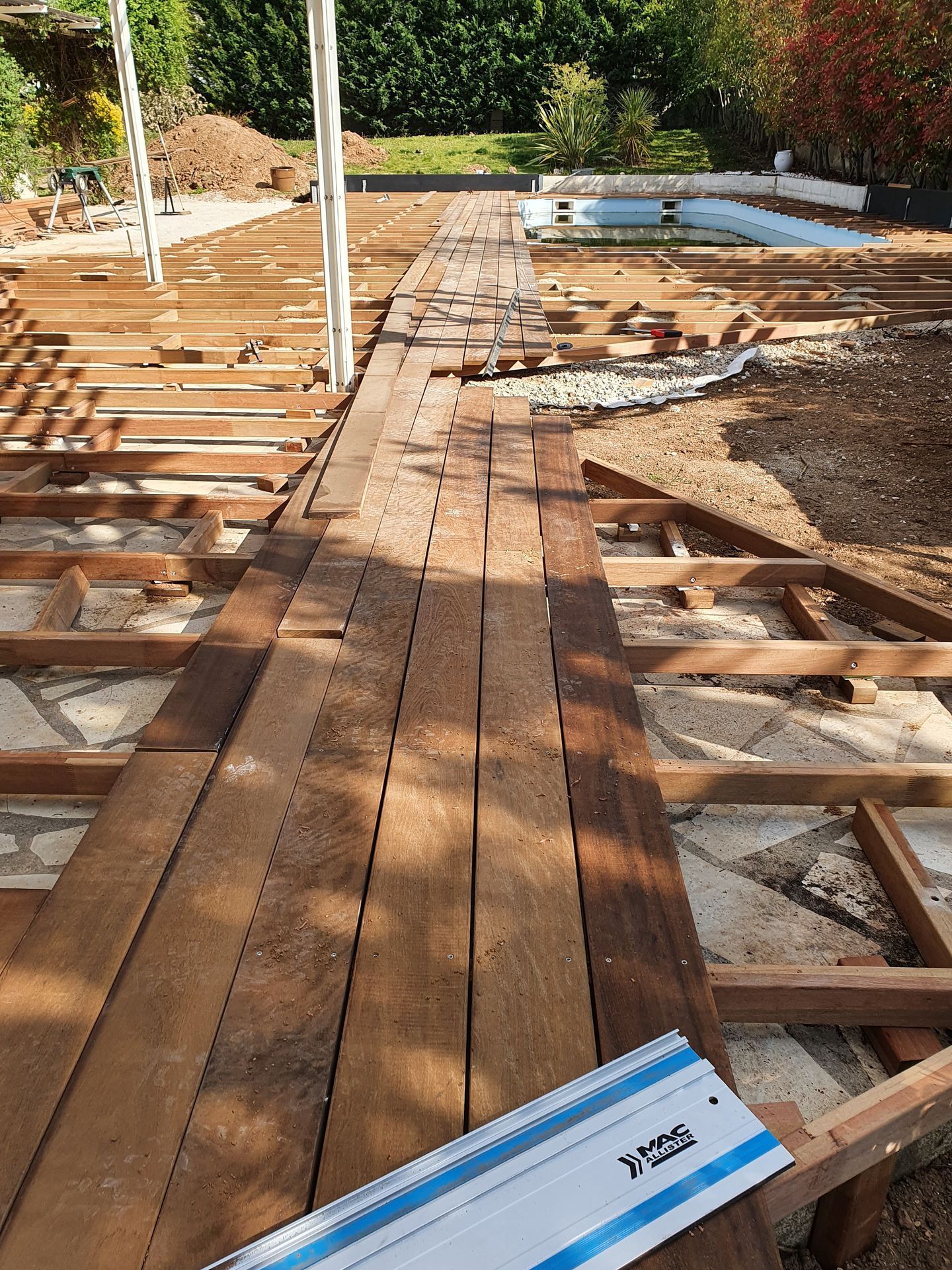 Charpente de terrasse en bois en construction, avec du bois et des outils empilés sur un site ensoleillé